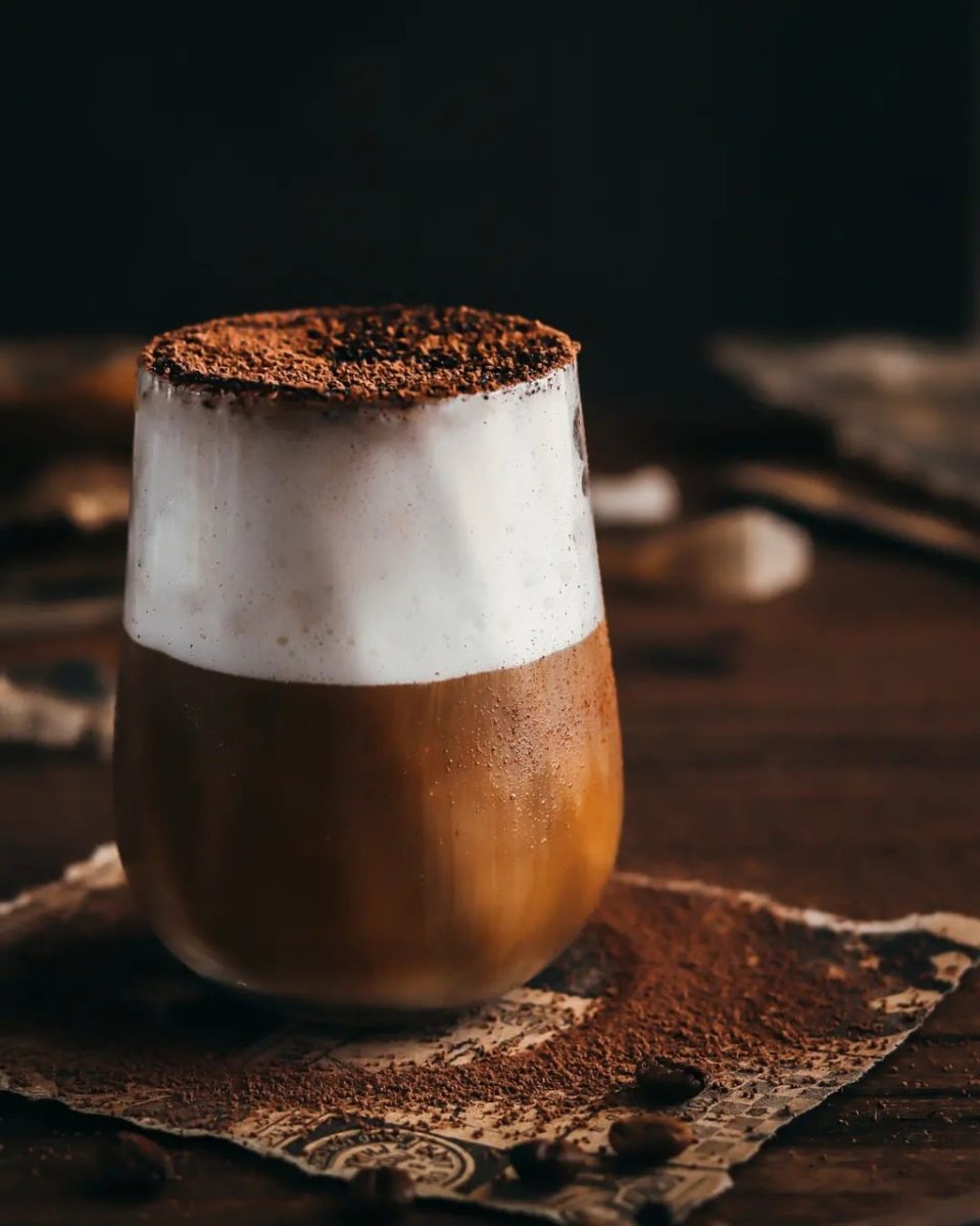 cappuccino, glass, milk foam, chocolate powder, layered coffee, coffee beans, wooden table, dark photography, coffee art, morning ritual, dense foam, morning coffee, cocoa dust, drawing, artwork, kitchen decor, artistic impression, nordic eclectic, vintage script, soft light