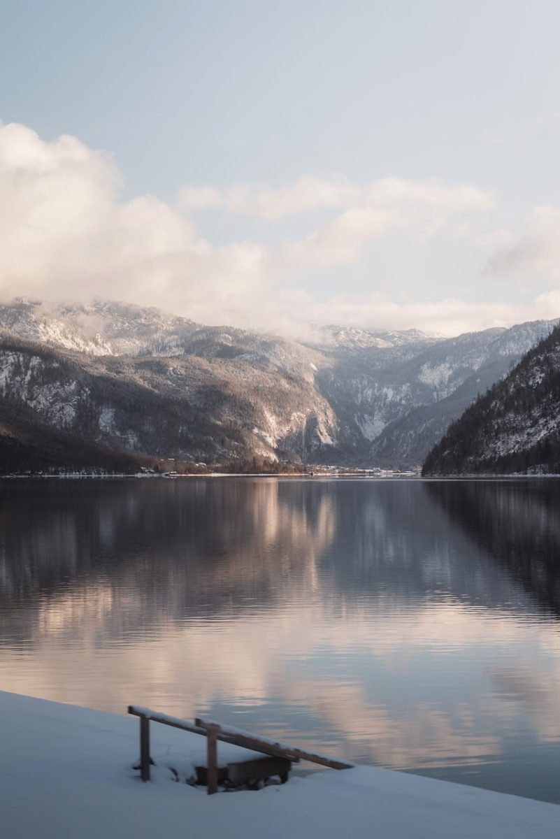 snow covered lake, mountain reflection, winter landscape, calm water, mist, soft light, cloudy sky, peaceful, tranquil, natural beauty, postcard, water reflection, peaceful landscape, snowy mountains, winter calm, afternoon light, meditative, calm lake, cloud reflection