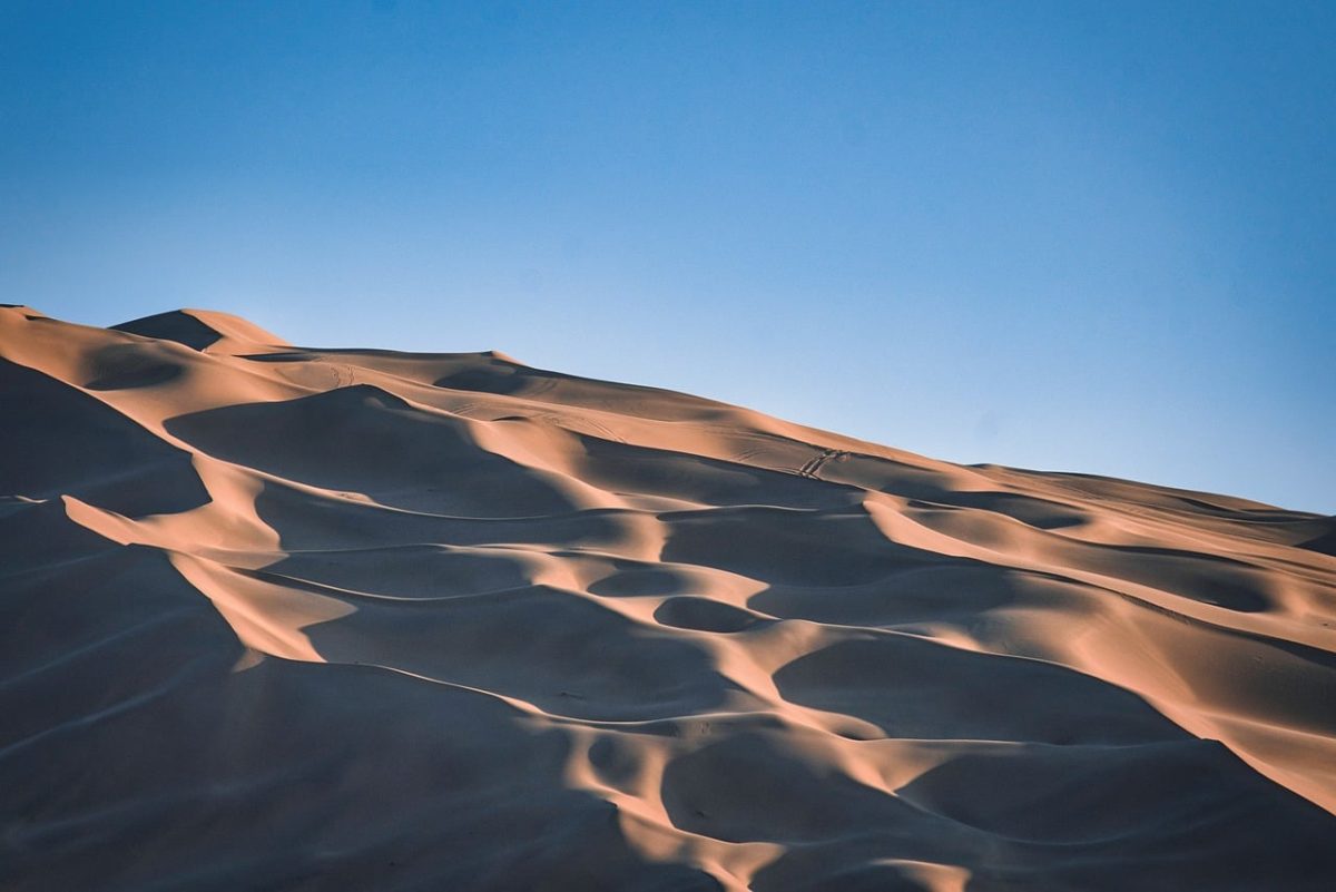 desert, sand dunes, light blue sky, desert landscape, light reflections, shadows, sand waves, natural landscape, no people, silence, desolate area, loneliness, nature, aridity, horizon, lonely landscape, summer day, peaceful atmosphere, golden tones, warmth