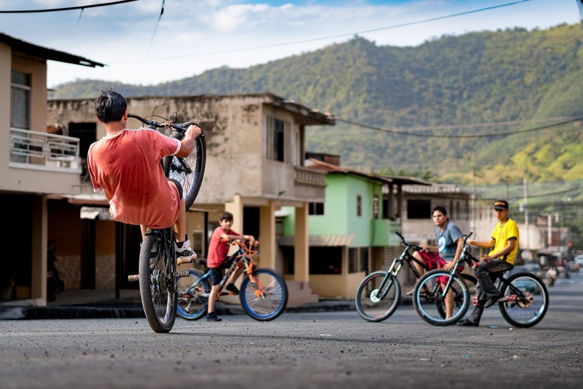 cyclist, bicycle, trick, nature, town, youth, mountains, skill, leisure, summer, friendship, fun, urban scene, wheelie, adrenaline, team sport, community, balance, creativity, local, young