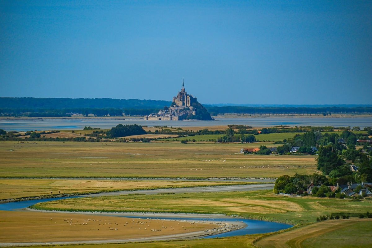 mont saint-michel, normandy, historic architecture, abbey, island community, medieval fortress, unesco world heritage, sheep, meadow, natural landscape, tower, abbey on a hill, landscape with streams, tourist attraction, church architecture, famous landmark, mediterranean climate, vineyard, culture