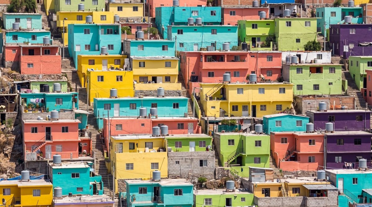 colorful houses, urban architecture, vibrant colors, eclectic style, latin america, sunny day, neighborhood, hilly terrain, wide angle, entrance level, concrete stairs, landmark, iconic site, tourist destination, camera photography, urban environment, elevation, enclosed space, roof patterns