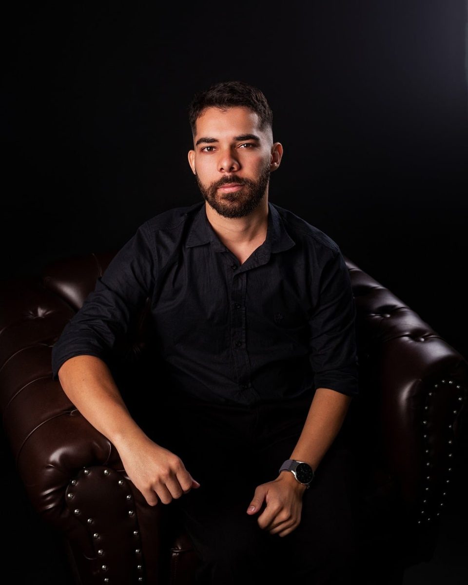 portrait, man, dark background, leather armchair, beard, smile, black shirt, leather chair, light, fashion, hairy arm, serious, atmosphere, expression, detail, low lighting, comfort, pose, indoors, professional