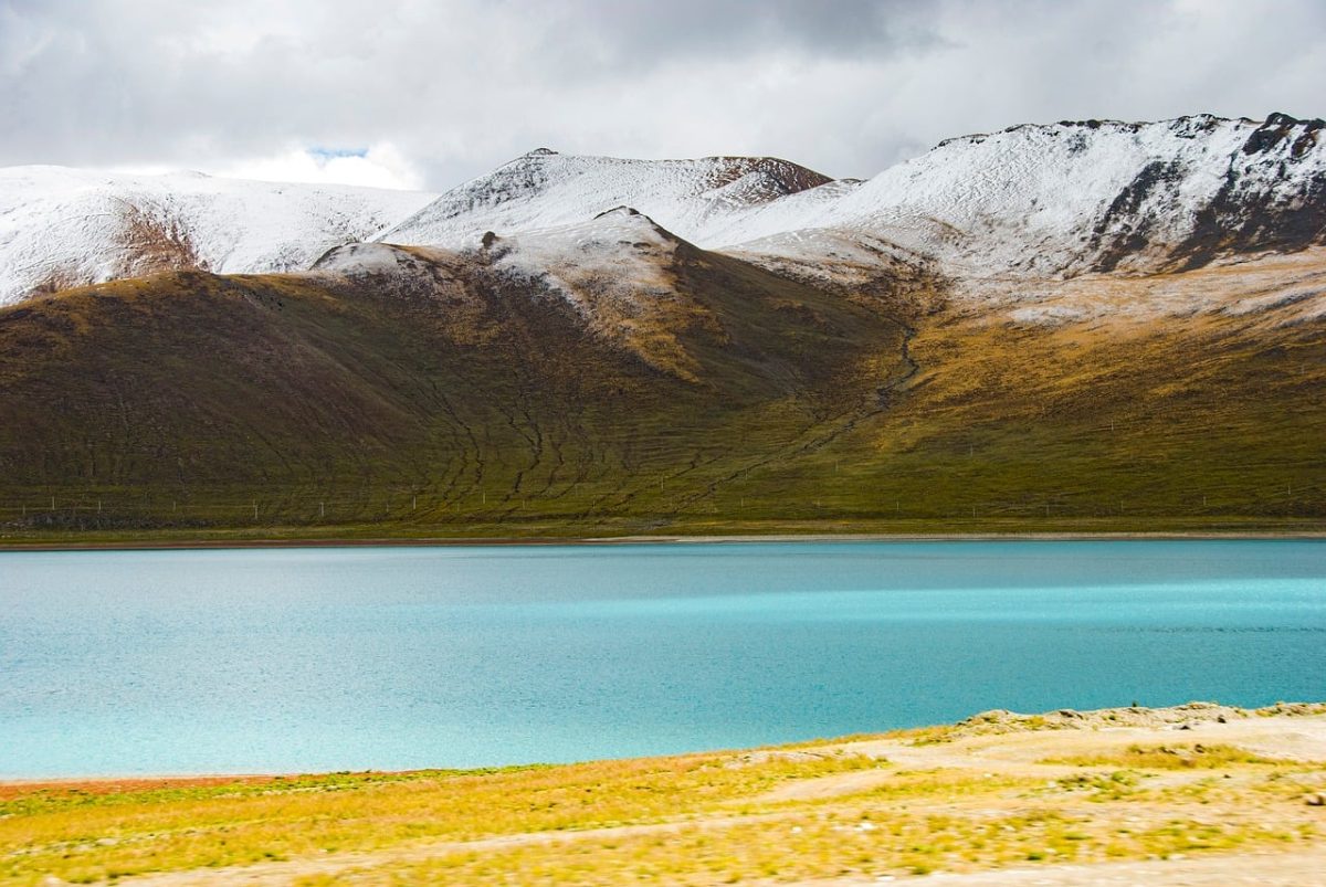 yamdrok, lake, tibet, sacred lake, turquoise water, snow-covered mountains, alpine meadow, rugged landscape, high elevation, cloudy sky, pastureland, wilderness, mountain range, mountain meadow, nature photography, nature, landscape, natural beauty, tranquility, seclusion, aerial view