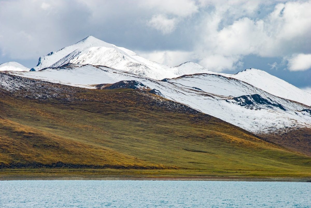 snow-capped mountains, alpine pasture, grass hills, high-altitude plateau, turquoise lakeshore, plateau wilderness, cloudy sky, tibetan landscape, azure lake, carolingian area