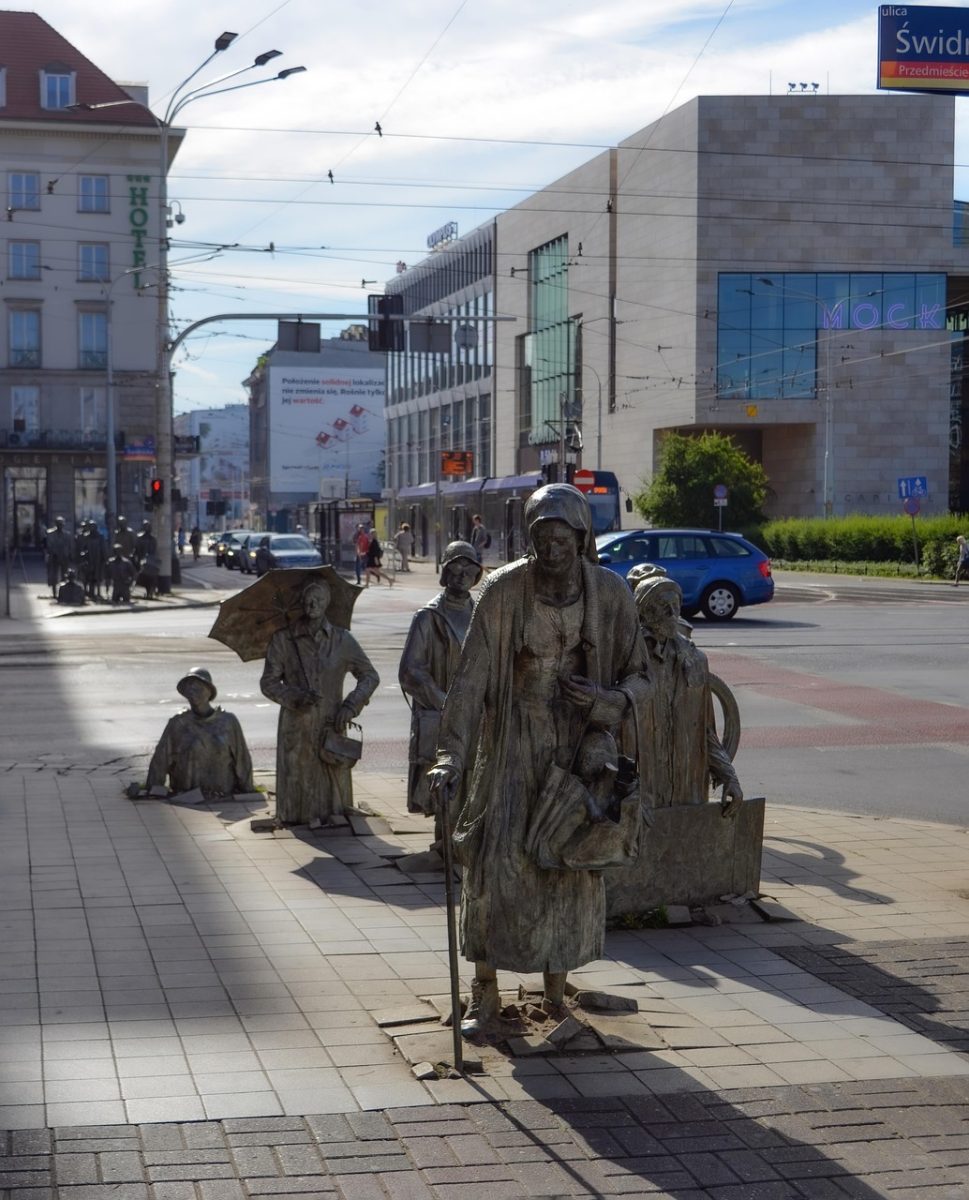 cityscape, monument, passerby, sidewalk, sculptures, metal, article, artistic, characters, people, urban, street, buildings