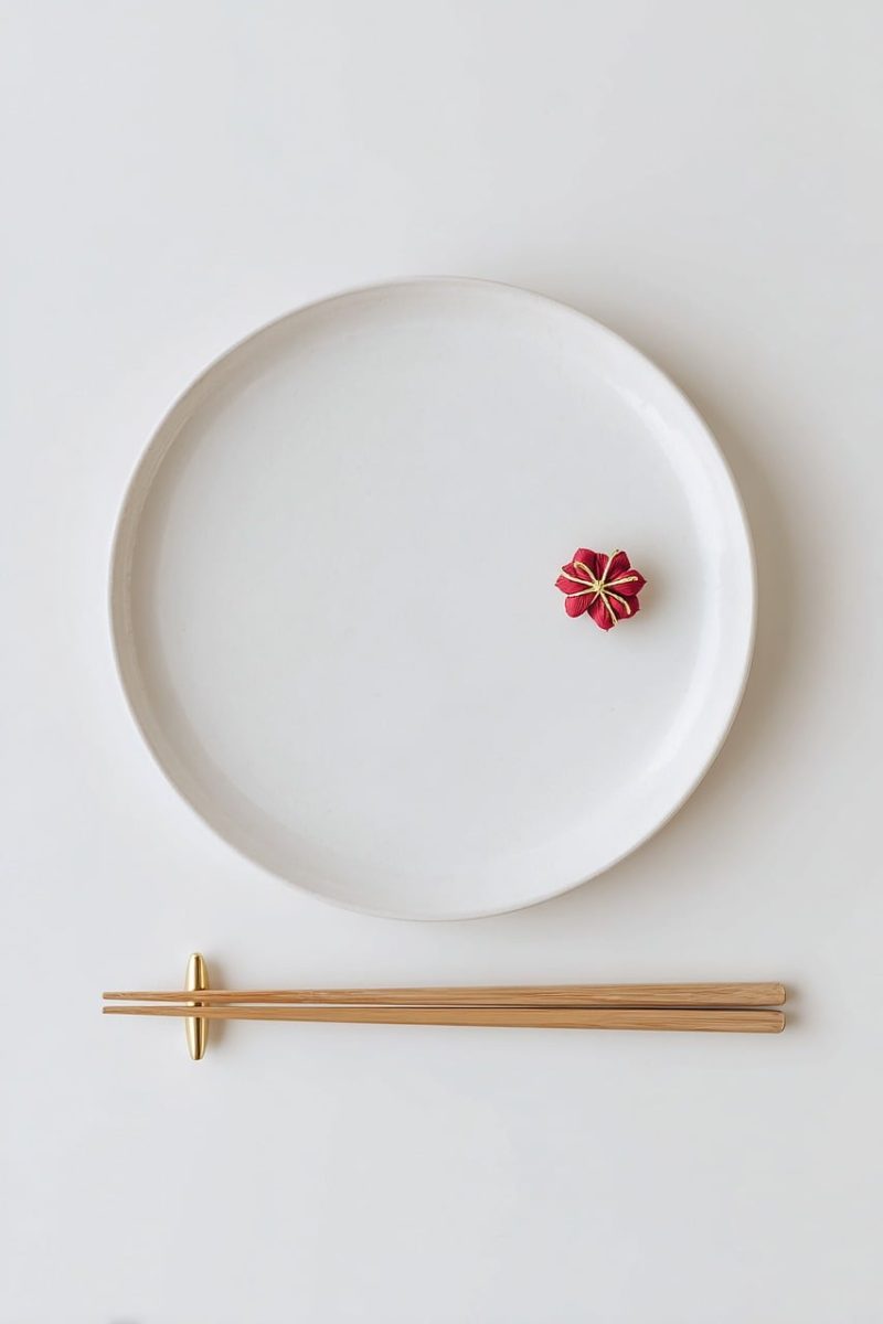 japanese new year, minimal, white plate, chopsticks, gold chopstick rest, mizuhiki, red decoration, flat lay, top view, clean, modern, celebration, copy space, zen, neutral, high resolution, food background, postcard, design template, table setting