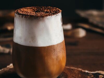 cappuccino, glass, milk foam, chocolate powder, layered coffee, coffee beans, wooden table, dark photography, coffee art, morning ritual, dense foam, morning coffee, cocoa dust, drawing, artwork, kitchen decor, artistic impression, nordic eclectic, vintage script, soft light
