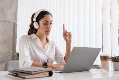 online education, video call, work environment, headphones, laptop, online meeting, young woman, remote worker, desk, office environment, working from home, teacher, online course, digital communication, coffee, work desk, distance learning, drinking coffee, raised finger