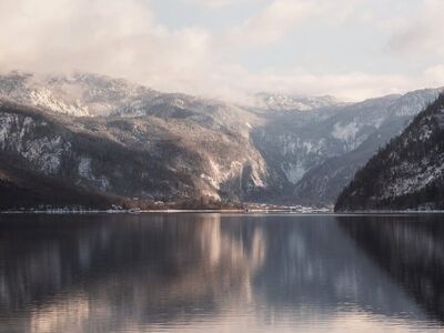 snow covered lake, mountain reflection, winter landscape, calm water, mist, soft light, cloudy sky, peaceful, tranquil, natural beauty, postcard, water reflection, peaceful landscape, snowy mountains, winter calm, afternoon light, meditative, calm lake, cloud reflection