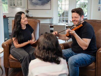 music, violin, home, family, comfort, happy, friendship, sitting, laughing, black t-shirt, weekday, privacy, hobby, entertainment, sofa, indoor, casual, relaxation, interactive, social