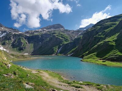 lake, mountain, valley, mountain landscape, blue sky, sunny day, green grass, snow-capped mountains, hiking, natural beauty, peaceful environment, tourist destination, clear water, summer day, panoramic view, nature, calm, tourist area, clean air, retreat