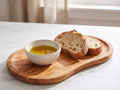 bread, olive oil, sourdough, natural light, wooden board, appetizer, breakfast, snack, mediterranean food, rustic, home cooking, healthy eating, fresh baked, simple meal, dipping, healthy, fresh, herb oil, focus, still life