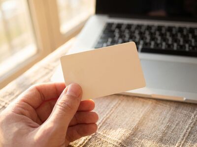 hand, business card, computer, laptop, window, table, hand with business card near laptop, work surface, office desk, close-up, hand work, keyboard, blank business card, daylight illumination, top view, office environment, holding, casual business, side lighting