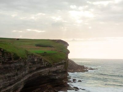 cliffs, ocean, waves, rocky shore, clouds, sky, scenery, coast, cliffside, calm sea, natural beauty, sunrise, nature reserve, ecosystem, climate zone, wildlife, nature, travel, eco-tourism, climate