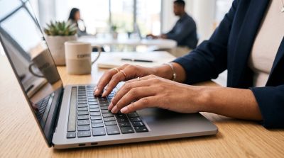 laptop, typing, hands, woman, office, desk, workspace, work desk, office environment, business, coffee mug, plant, close-up, employee, professional, technology, modern, nature, digital, multitasking, industry