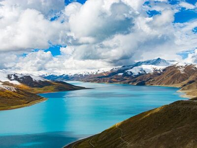 yamdrok lake, tibet, sacred lake, turquoise water, mountain landscape, snow-capped mountains, high altitude, untouched nature, cumulus clouds, mountain road, nature, tibetan plateau, scenery, water, natural beauty, blue sky, view, alpine scenery, natural wonder, tourist attraction