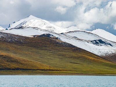 snow-capped mountains, alpine pasture, grass hills, high-altitude plateau, turquoise lakeshore, plateau wilderness, cloudy sky, tibetan landscape, azure lake, carolingian area