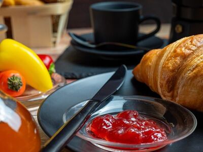 breakfast, croissant, jam, honey, coffee machine, coffee pot, black dishes, bread basket, bun, paprika, tomatoes, rustic table, baked goods, morning meal, mediterranean, comfortable, food scene, enjoyment, café atmosphere