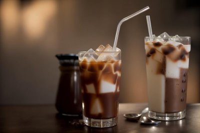 iced coffee, metal straw, ice, coffee, milk, espresso, cold drink, coffee beans, dark background, moody lighting, coffee and milk, glass, swirling milk, coffee brewing art, coffee shop, slow motion, close-up, comfort drink, elegant look, toward plastic bans