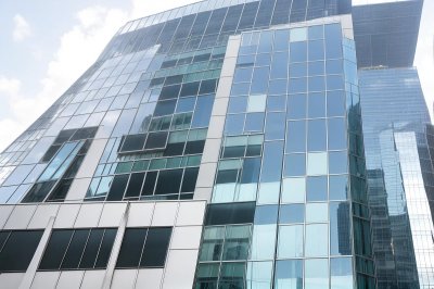 window cleaning, modern architecture, glass building, skyscraper construction, building maintenance, high-rise worker, urban landscape, building facade, urban climbing, safety equipment, rope work, cleanliness, workwear, weather conditions, outdoor work, access systems, tall buildings, architectural design, office building, blue glass